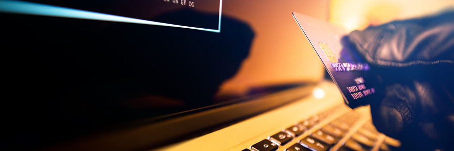 credit card thief using card in front of computer