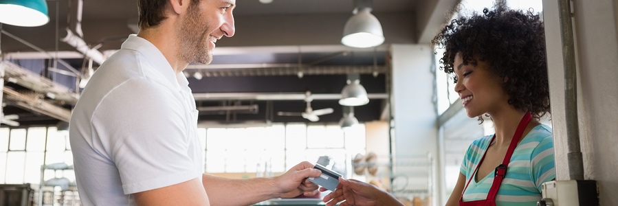 Smiling customer paying by credit card at the bakery
